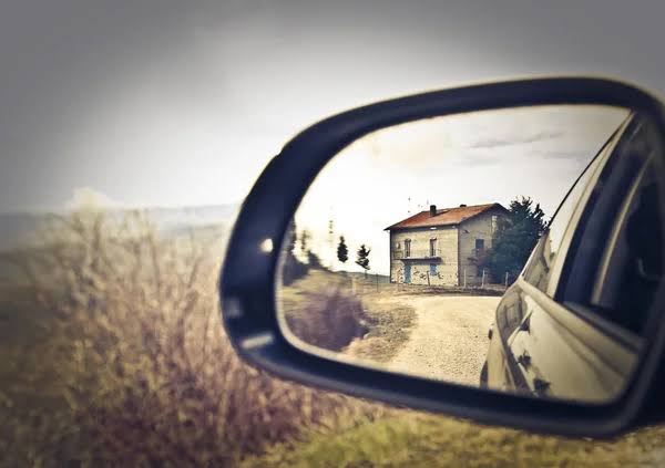 Rear view mirror showing image of a home